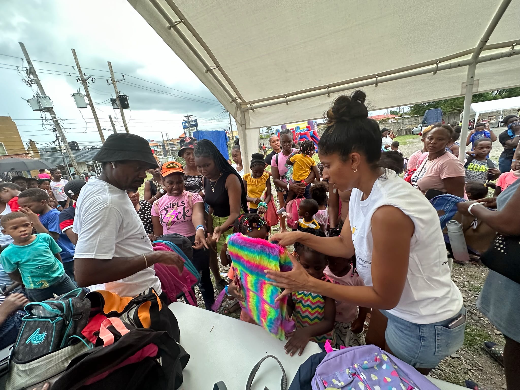 Melody and Junior McLymont distributing colourful backpacks to children and families