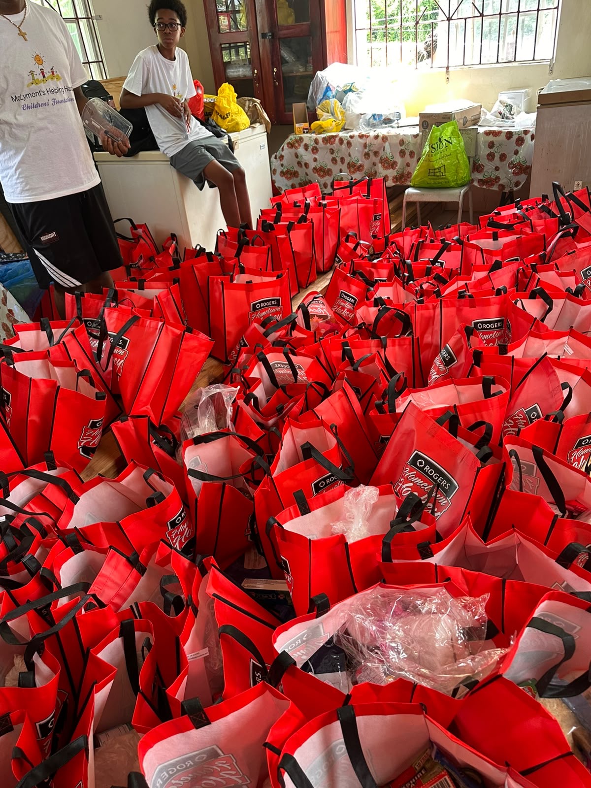 Volunteers surrounded by rows of red care bags prepared for community distribution